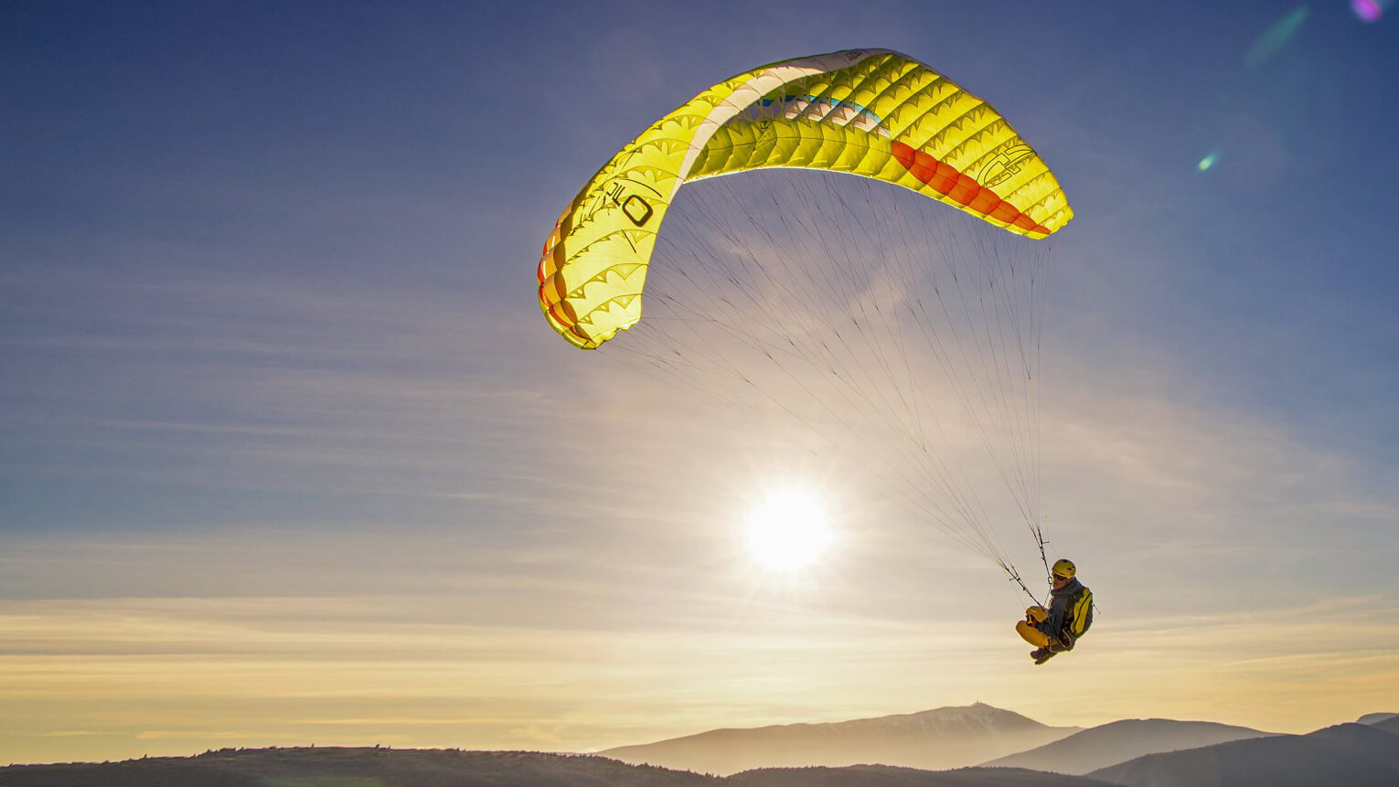 Parapente con fondo de montañas al atardecer