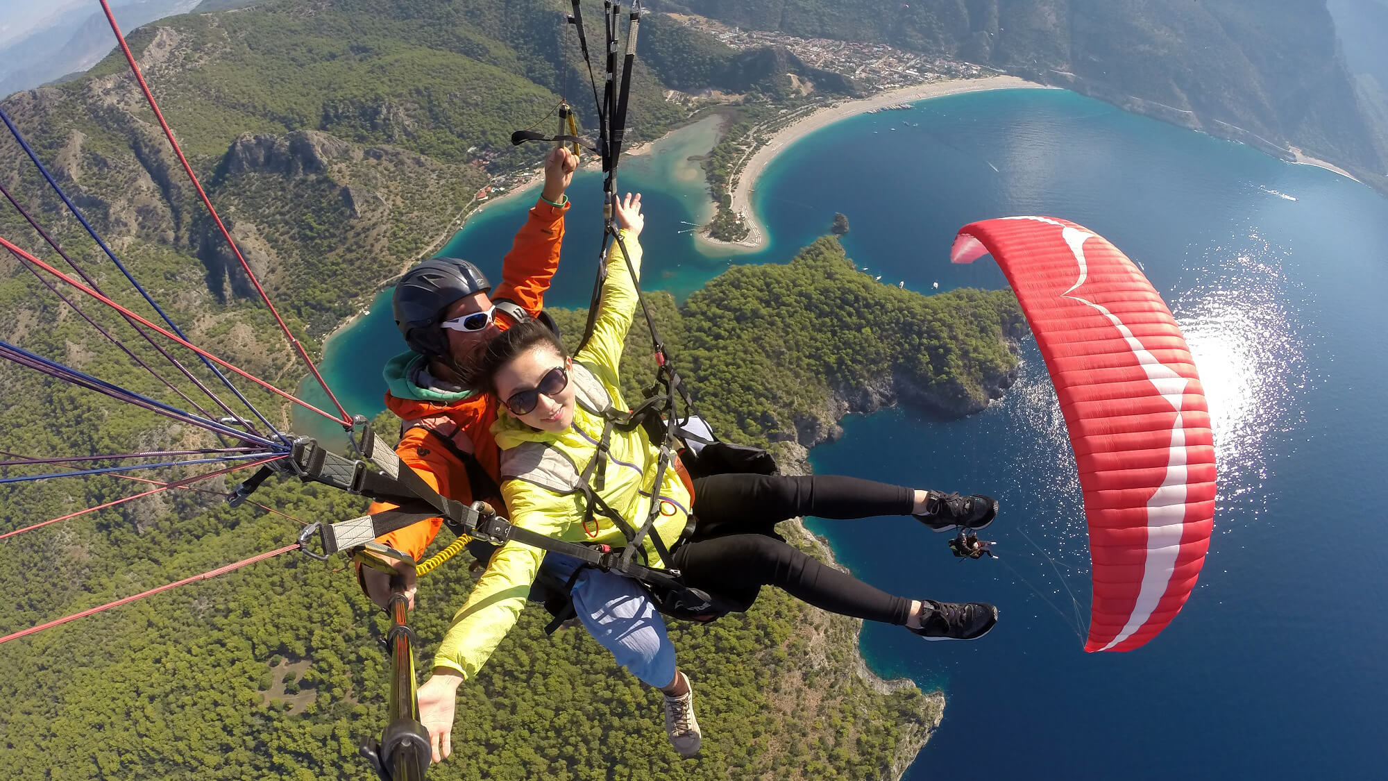 Dos personas en un parapente con fondo de montañas al atardecer