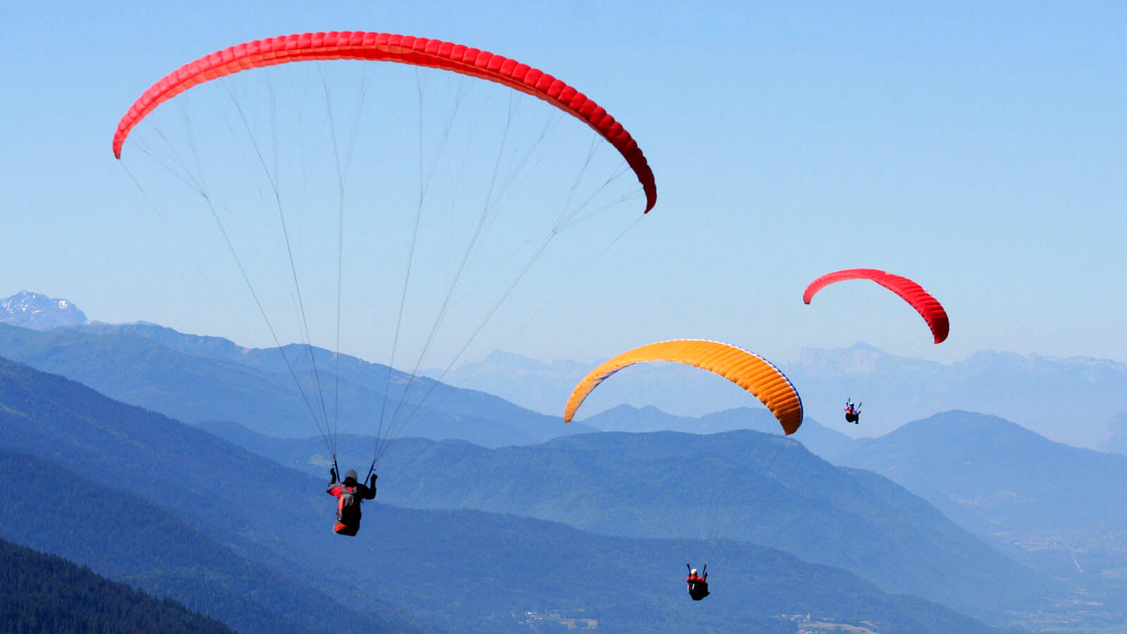 Tres parapente con fondo de montañas