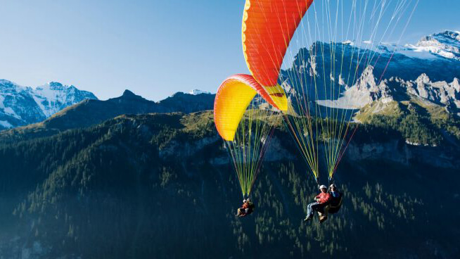Dos parapente con fondo de montañas