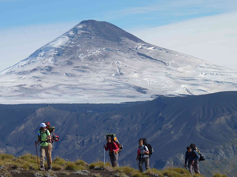 Gente haciendo trekking con volcán de fondo